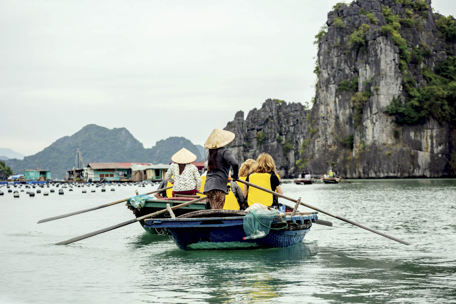 Bai Tu Long, Vietnam, Tourists on wooden row boats, pearl farm buoys and limestone (karst) mounds), Vung Vieng fishing village, Ha Long Bay, Bai Tu Long Sector, near Ha Long Bay