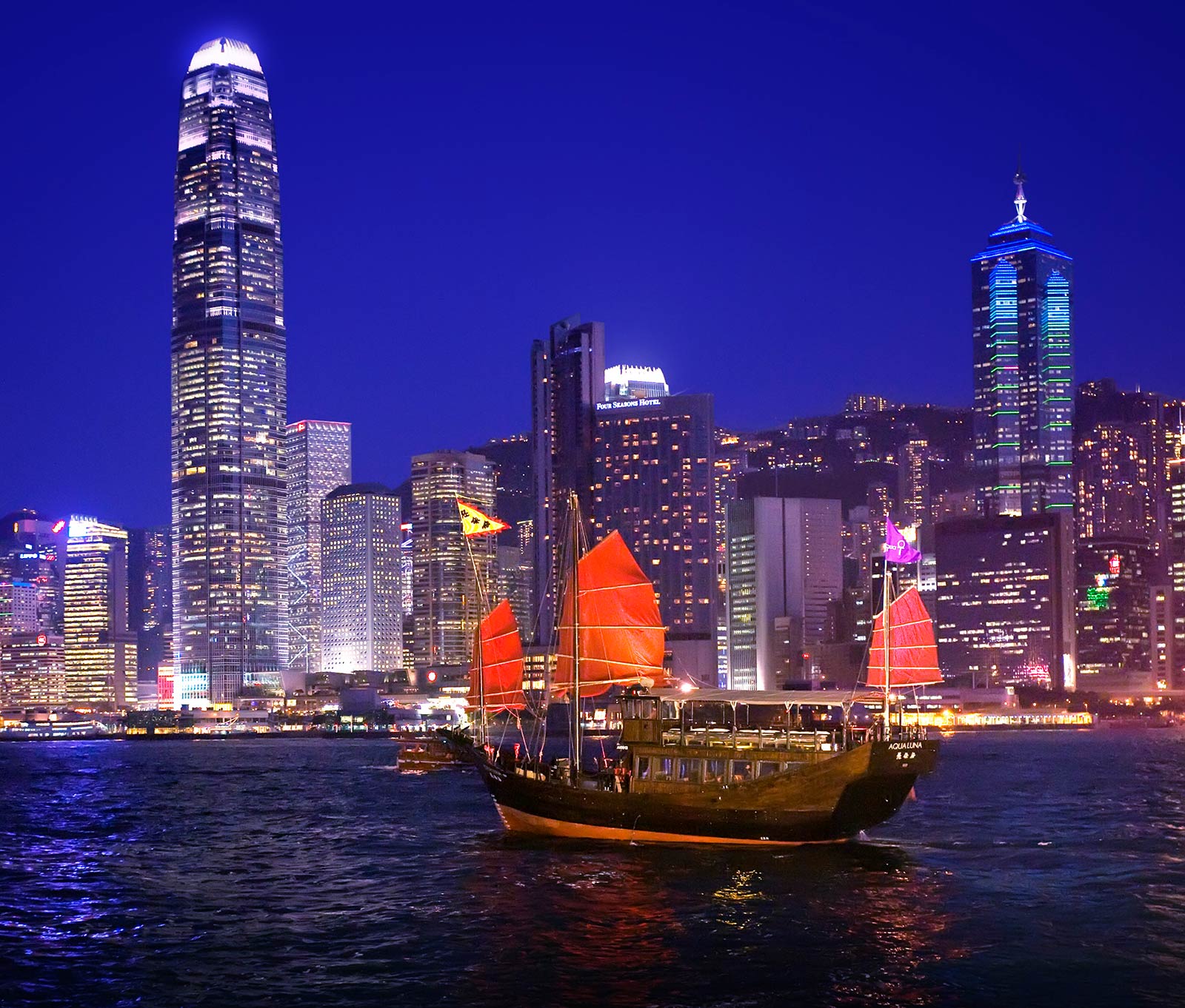 Hong Kong skyline at night with the Aqua Luna boat on Victoria Harbour