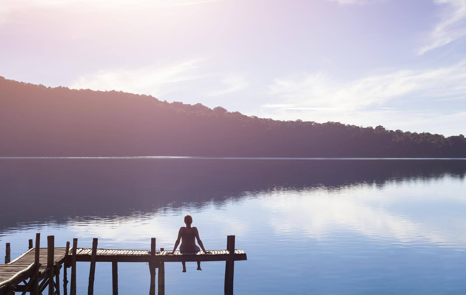 Woman sat looking out over serene lake