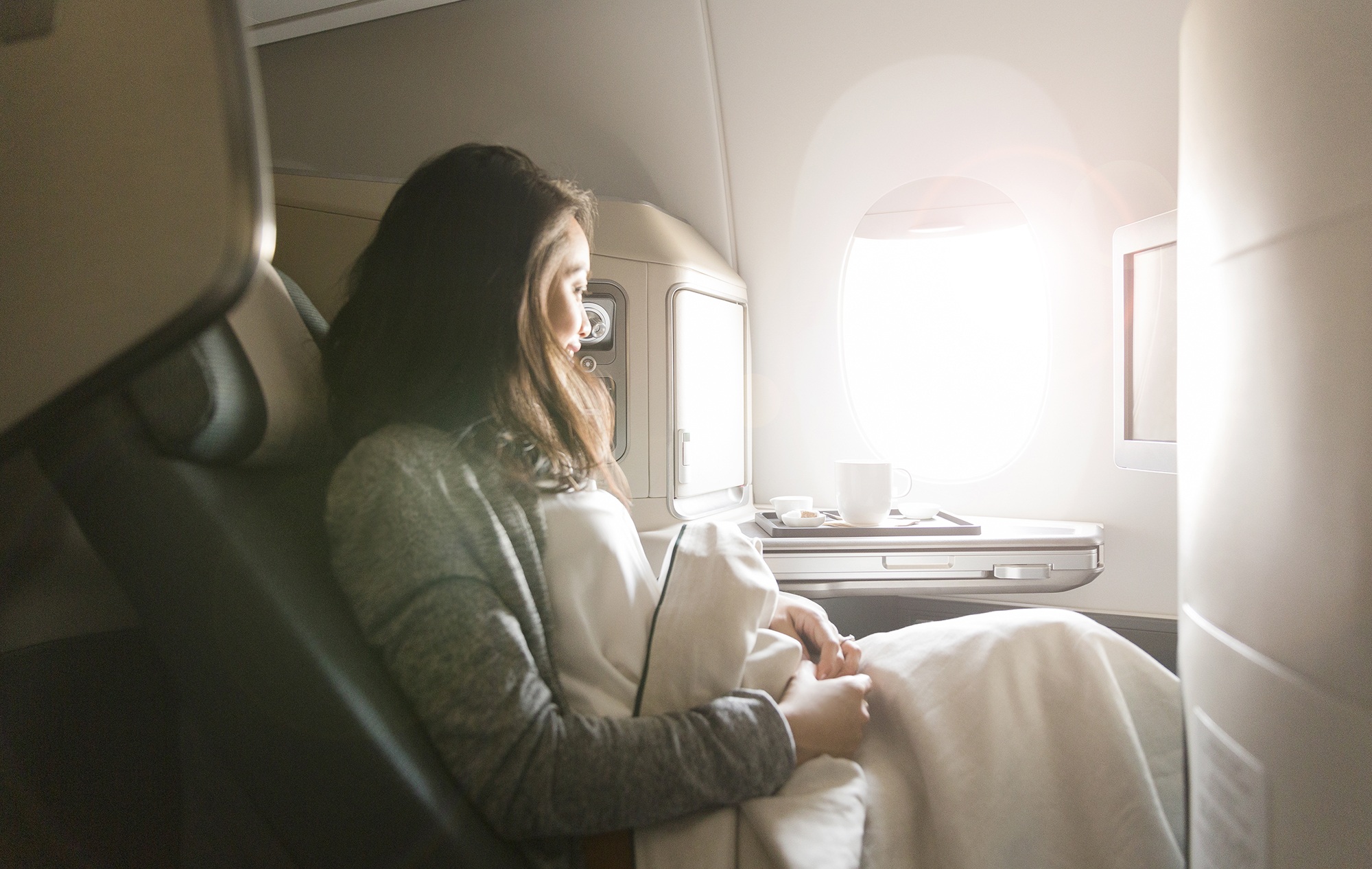 Woman under blanket on Cathay Pacific flight looking out window